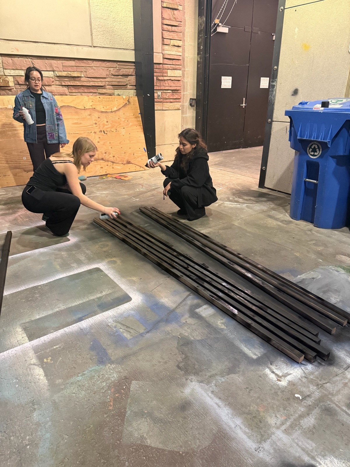 Team spray-painting wood strips for the exhibit's base